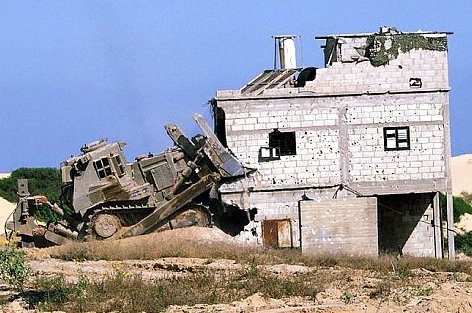 An IDF Caterpillar D9 armored bulldozer demolishing a house in the Gaza Strip during the Second Intifada